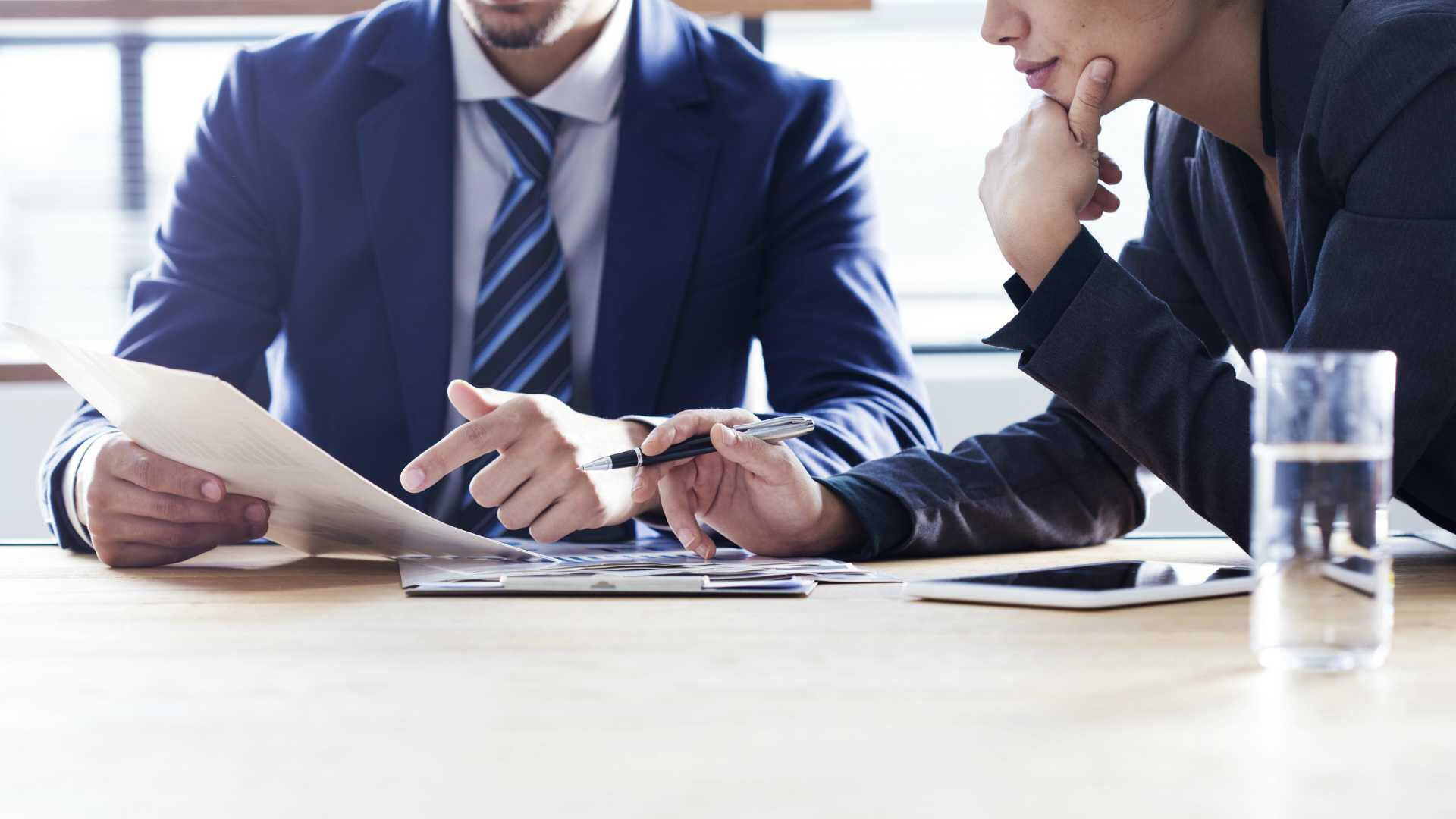 Two Business Professionals Perusing GRE Exam Related Reports Provided By A Private Tutor