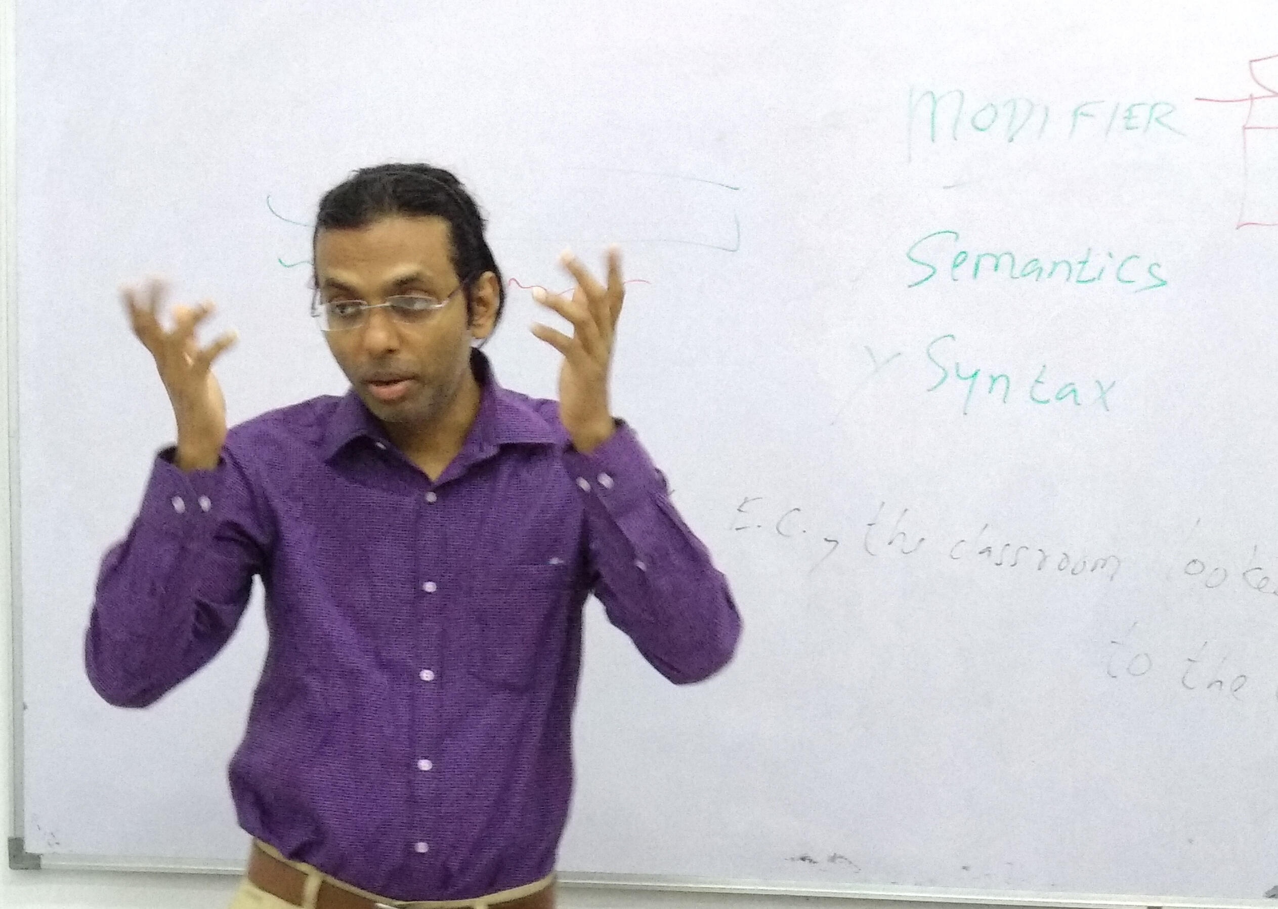 Neelesh Kumar Ray teaching verbal reasoning in a classroom with a whiteboard behind him.